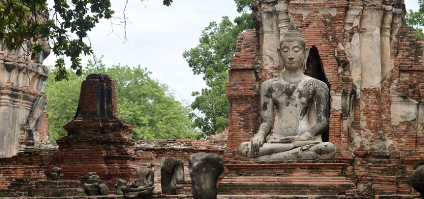 Ancienne statue de Bouddha sur un site historique en ruines de briques.