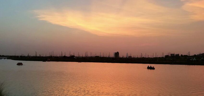 Rivière calme, silhouettes de coucher de soleil, ciel orange-rose.