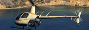 Hélicoptère Robinson R22 gris en vol au-dessus de la mer