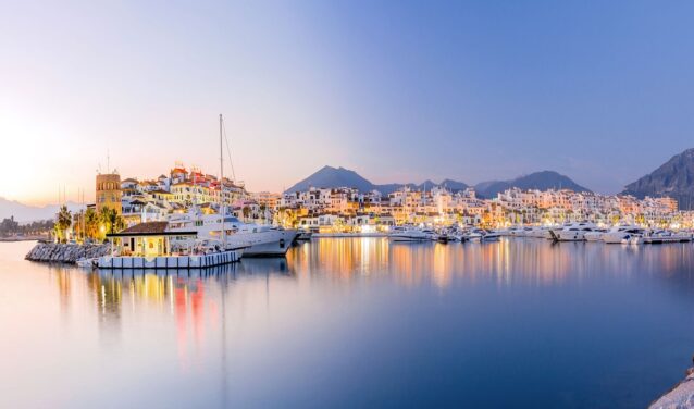 Marina de Puerto Banus au crépuscule, yachts amarrés, toile de fond de montagne.
